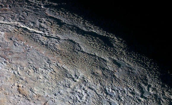 In this extended color image of Pluto taken by NASA’s New Horizons spacecraft, rounded and bizarrely textured mountains, named the Tartarus Dorsa, rise up along Pluto’s day-night terminator and show intricate but puzzling patterns of blue-gray ridges and reddish material in between. This view, roughly 330 miles (530 km) across, combines blue, red and infrared images taken by New Horizons’ Ralph/Multispectral Visual Imaging Camera on July 14, 2015. Image credit: NASA / Johns Hopkins University Applied Physics Laboratory / Southwest Research Institute.
