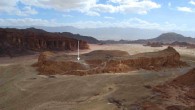 Slaves’ Hill in the center of the Timna Valley (looking east); the black slag mounds on the hilltop are visible, as well as the only access path to the site; the arrow indicates the gatehouse complex. Image credit: Erez Ben-Yosef et al.
