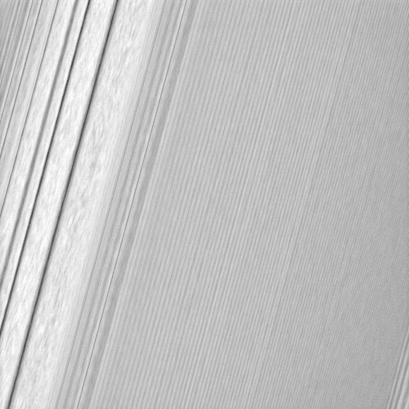 This Cassini image features a density wave in Saturn’s A ring (at left) that lies around 83,575 miles (134,500 km) from Saturn. Density waves are accumulations of particles at certain distances from the planet. This feature is filled with clumpy perturbations, which researchers informally refer to as ‘straw.’ The wave itself is created by the gravity of Saturn’s moons Janus and Epimetheus, which share the same orbit around the gas giant. Elsewhere, the scene is dominated by ‘wakes’ from a recent pass of the ring moon Pan. The image was taken in visible light with Cassini’s wide-angle camera on December 18, 2016. The view was obtained at a distance of approximately 34,000 miles (56,000 km) from the rings and looks toward the unilluminated side of the rings. Image credit: NASA / JPL-Caltech / Space Science Institute.