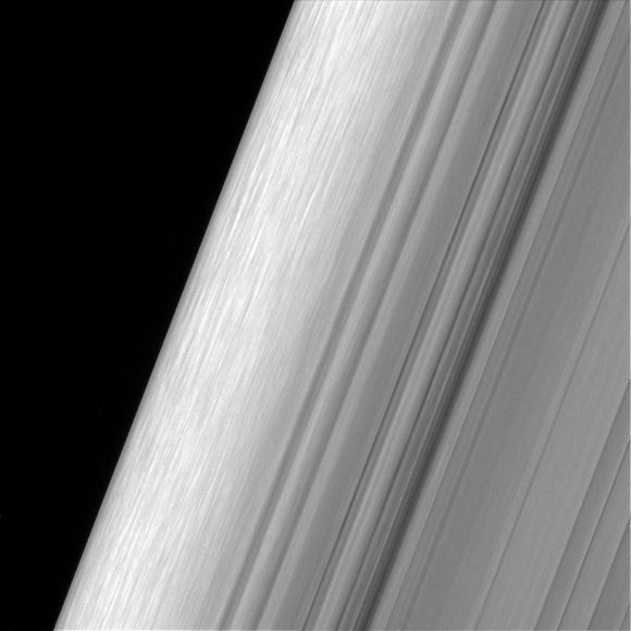 This image shows a region in Saturn’s outer B ring. Cassini viewed this area at a level of detail twice as high as it had ever been observed before. The view here is of the outer edge of the B ring, at left, which is perturbed by the most powerful gravitational resonance in the rings: the ‘2:1 resonance’ with Saturn’s icy moon Mimas. This means that, for every single orbit of Mimas, the ring particles at this specific distance from Saturn orbit the planet twice. This results in a regular tugging force that perturbs the particles in this location. A lot of structure is visible in the zone near the edge on the left. This is likely due to some combination of the gravity of embedded objects too small to see, or temporary clumping triggered by the action of the resonance itself. Scientists informally refer to this type of structure as ‘straw.’ This image was taken using a fairly long exposure, causing the embedded clumps to smear into streaks as they moved in their orbits. Later Cassini orbits will bring shorter exposures of the same region, which will give researchers a better idea of what these clumps look like. But in this case, the smearing does help provide a clearer idea of how the clumps are moving. The image was taken in visible light with Cassini’s wide-angle camera on December 18, 2016. The view was obtained at a distance of approximately 32,000 miles (52,000 km) from the rings and looks toward the unilluminated side of the rings. Image credit: NASA / JPL-Caltech / Space Science Institute.