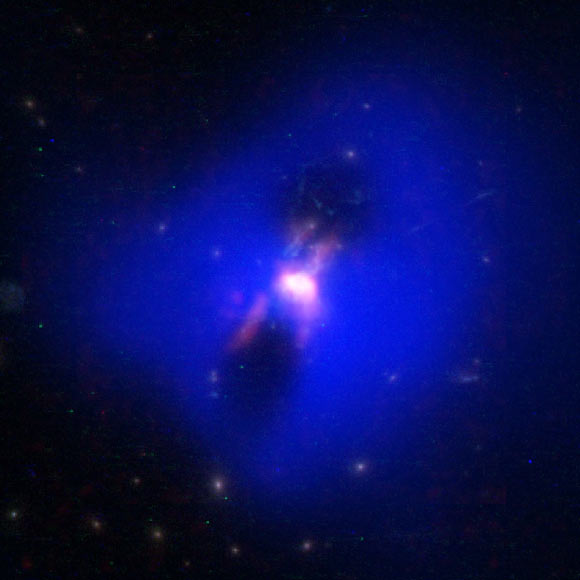 Composite image showing how powerful radio jets from the supermassive black hole at the center of a galaxy in the Phoenix Cluster inflated huge ‘bubbles’ in the hot, ionized gas surrounding the galaxy (the cavities inside the blue region imaged by NASA's Chandra X-ray observatory). Hugging the outside of these bubbles, ALMA discovered an unexpected trove of cold gas, the fuel for star formation (red). The background image is from the NASA/ESA Hubble Space Telescope. Image credit: ALMA / ESO / NAOJ / NRAO / NASA / ESA / Hubble / CXC / MIT / H. Russell et al / M. McDonald et al / B. Saxton.