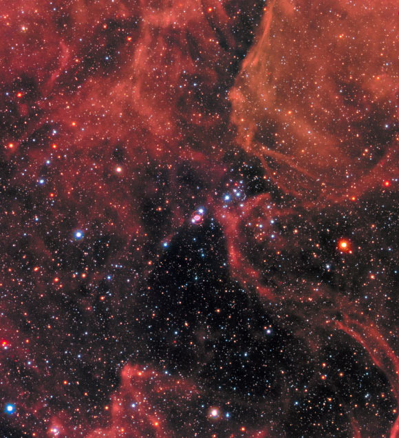 This Hubble image shows the remnant of SN 1987A within the Large Magellanic Cloud, a satellite galaxy of the Milky Way. The image was taken by Hubble’s Wide Field Camera 3 (WFC3) in January 2017. SN 1987A is located in the center of the image amidst a backdrop of stars. The bright ring around the central region of the exploded star is composed of material ejected by the star about 20,000 years before the actual explosion took place. The supernova is surrounded by gaseous clouds. The clouds’ red color represents the glow of hydrogen gas. The colors of the foreground and background stars were added from observations taken by Hubble’s Wide Field Planetary Camera 2 (WFPC2). Image credit: NASA / ESA / R. Kirshner, Harvard-Smithsonian Center for Astrophysics and Gordon and Betty Moore Foundation / P. Challis, Harvard-Smithsonian Center for Astrophysics.
