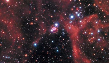 This Hubble image shows the remnant of SN 1987A within the Large Magellanic Cloud, a satellite galaxy of the Milky Way. The image was taken by Hubble’s Wide Field Camera 3 (WFC3) in January 2017. SN 1987A is located in the center of the image amidst a backdrop of stars. The bright ring around the central region of the exploded star is composed of material ejected by the star about 20,000 years before the actual explosion took place. The supernova is surrounded by gaseous clouds. The clouds’ red color represents the glow of hydrogen gas. The colors of the foreground and background stars were added from observations taken by Hubble’s Wide Field Planetary Camera 2 (WFPC2). Image credit: NASA / ESA / R. Kirshner, Harvard-Smithsonian Center for Astrophysics and Gordon and Betty Moore Foundation / P. Challis, Harvard-Smithsonian Center for Astrophysics.