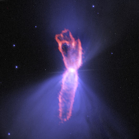 Composite image of the Boomerang Nebula: ALMA observations (orange) showing the hourglass-shaped outflow, which is embedded inside a roughly round ultra-cold outflow; the hourglass outflow stretches more than 1.9 trillion miles from end to end, and is the result of a jet that is being fired by the central star, sweeping up the inner regions of the ultra-cold outflow like a snow-plow; the ultra-cold outflow is about 10 times bigger. The ALMA data are shown on top of an image from the NASA/ESA Hubble Space Telescope (blue). Image credit: ALMA / ESO / NAOJ / NRAO / NASA / ESA / Hubble / AUI / NSF.