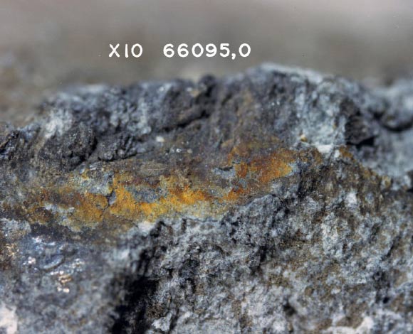 This is a close-up photo of metallic salts, or ‘rust,’ on surface of the Rusty Rock. Note the appearance of a crust under the colored salts. Magnification - 10x. Image credit: NASA.