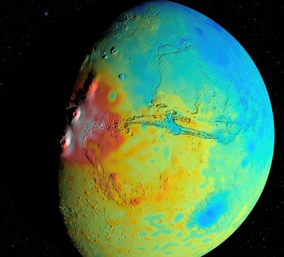 A new map of the thickness of the Martian crust shows less variation between thicker regions (red) and thinner regions (blue), compared to earlier mapping. This view is centered on Valles Marineris, with the Tharsis Montes near the terminator to its west. The map is based on modeling of Mars’ gravity field by Goossens et al. Image credit: NASA / Goddard / UMBC / MIT / E. Mazarico.