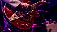 Musician on stage playing an electric guitar. Image credit: Herb1979.