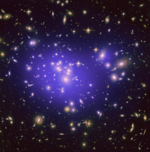 This Hubble image shows the inner region of Abell 1689, an immense cluster of galaxies located 2.2 billion light-years away. The cluster’s gravitational field is warping light from background galaxies, causing them to appear as arcs. Dark matter in Abell 1689, which represents about 80% of its mass, is mapped by plotting these arcs. Image credit: NASA / ESA / JPL-Caltech / Yale / CNRS.