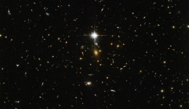 This Hubble image shows the massive galaxy cluster WHL J24.3324-8.477. The bright flash in the middle of the image is actually a star lying within our Milky Way Galaxy. Image credit: NASA / ESA / Hubble.