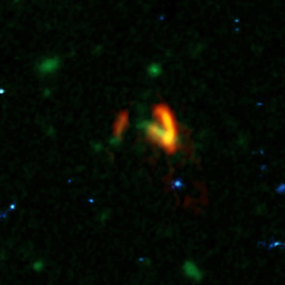 A composite image showing ALMA data (red) of the two galaxies of SPT-S J031132-5823.4. These galaxies are shown over a background from the NASA/ESA Hubble Space Telescope (blue and green). The ALMA data show the two galaxies’ dusty glow. The image of the galaxy on the right is distorted by gravitational lensing. The nearer foreground lensing galaxy is the green object between the two galaxies imaged by ALMA. Image credit: ALMA / ESO / NAOJ / NRAO / Marrone et al / B. Saxton / AUI / NSF / NASA / ESA / Hubble.