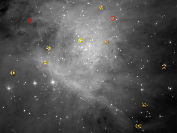 This image is part of a Hubble survey for low-mass stars, brown dwarfs, and planets in the Orion Nebula. Each symbol identifies a pair of objects, which can be seen in the symbol’s center as a single dot of light. Special image processing techniques were used to separate the starlight into a pair of objects. The thicker inner circle represents the primary body, and the thinner outer circle indicates the companion. The circles are color-coded: red for a planet; orange for a brown dwarf; and yellow for a star. Located in the upper left corner is a planet-planet pair in the absence of a parent star. In the middle of the right side is a pair of brown dwarfs. The portion of the Orion Nebula measures roughly 3 x 4 light-years. Image credit: NASA / ESA / G. Strampelli, STScI.