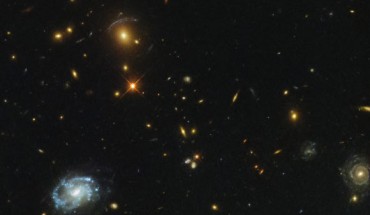 In the upper part of this Hubble image, the light from distant galaxies has been smeared and twisted into odd shapes, arcs, and streaks. This phenomenon indicates the presence of a massive galaxy cluster, SDSS J0150+2725, which is bending the light coming from the galaxies behind it with its monstrous gravitational influence. Image credit: NASA / ESA / Hubble / Judy Schmidt, www.geckzilla.com.