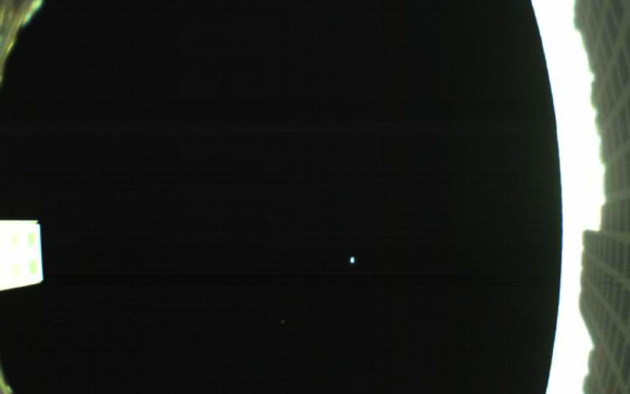 This image from NASA’s MarCO-B (known as ‘Wall-E’ to the MarCO team) CubeSat shows the spacecraft’s unfolded high-gain antenna at right and the Earth and the Moon in the center. Image credit: NASA / JPL-Caltech.