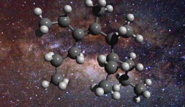 An illustration of the structure of a greasy carbon molecule, set against an image of the Milky Way’s center, where this material has been detected; carbon is represented as gray spheres and hydrogen as white spheres. Image credit: D. Young.