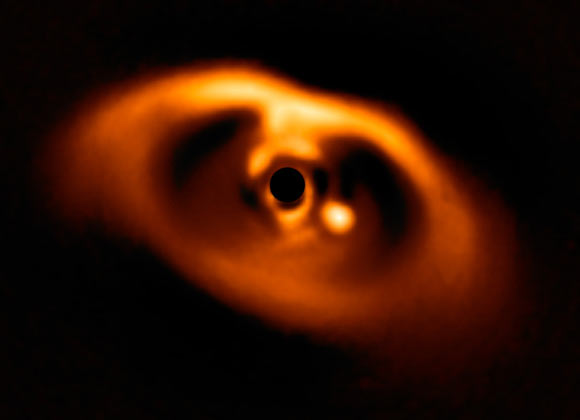 This image from the SPHERE instrument on ESO’s Very Large Telescope is the first clear image of an exoplanet caught in the very act of formation. The planet stands clearly out, visible as a bright point to the right of the center of the image, which is blacked out by the coronagraph mask used to block the blinding light of the central star. Image credit: ESO / A. Müller et al.
