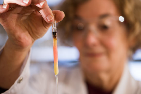 Biogeochemist Dr. Janet Hope holds an ampoule with pink colored porphyrins. Image credit: Australian National University.