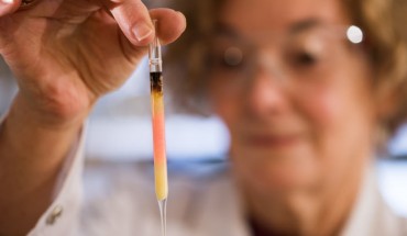 Biogeochemist Dr. Janet Hope holds an ampoule with pink colored porphyrins. Image credit: Australian National University.