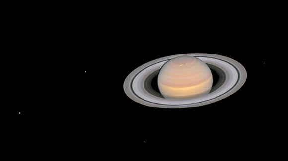 This composite image, taken by Hubble on June 6, 2018, shows the ringed planet Saturn with six of its 62 known moons. From left to right, the moons visible in this image are Dione, Enceladus, Tethys, Janus, Epimetheus, and Mimas. The moons seen here are all icy and cratered. Enceladus is considered a candidate for the existence of primitive life because it is outgassing water vapor from a subsurface ocean. Based on data from the Cassini mission to Saturn, scientists hypothesise that a small, wayward moon like one of these disintegrated 200 million years ago to form Saturn’s ring system. The image is a composite because the moons move during the Saturn exposures, and individual frames must be realigned to make a color portrait. Image credit: NASA / ESA / A. Simon, NASA’s Goddard Space Flight Center / OPAL Team / J. DePasquale, STScI.
