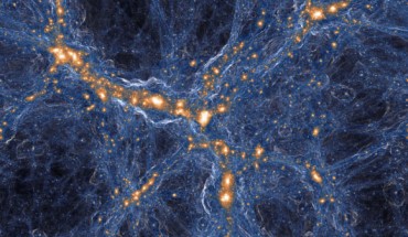 Computer simulation of a region of the Universe wherein a low-density ‘void’ (dark blue region at top center) is surrounded by denser structures containing numerous galaxies (orange/white). Image credit: TNG Collaboration.