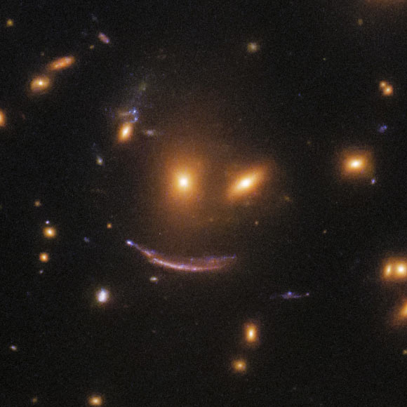 SDSS J0952+3434’s gravity magnifies and distorts a very distant galaxy, which is approximately 11 billion light-years away.  Image credit: NASA / ESA / Hubble / Judy Schmidt, www.geckzilla.com.