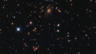 This Hubble image shows the massive galaxy cluster SDSS J1110+6459, which is located about 6 billion light-years from Earth. The image includes optical and infrared observations from Hubble’s Wide Field Camera 3 (WFC3). Four filters were used to sample various wavelengths. The color results from assigning different hues to each monochromatic image associated with an individual filter. Image credit: NASA / ESA / Hubble / Judy Schmidt, www.geckzilla.com.