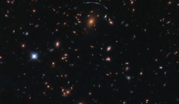 This Hubble image shows the massive galaxy cluster SDSS J1110+6459, which is located about 6 billion light-years from Earth. The image includes optical and infrared observations from Hubble’s Wide Field Camera 3 (WFC3). Four filters were used to sample various wavelengths. The color results from assigning different hues to each monochromatic image associated with an individual filter. Image credit: NASA / ESA / Hubble / Judy Schmidt, www.geckzilla.com.