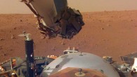 This image from InSight’s robotic-arm mounted Instrument Deployment Camera shows the instruments on the spacecraft’s deck, with the Martian surface of Elysium Planitia in the background. The color-calibrated picture was acquired on December 4, 2018 (Sol 8); in the foreground, a copper-colored hexagonal cover protects the SEIS seismometer; the gray dome behind SEIS is the wind and thermal shield, which will be placed over SEIS; to the left is a black cylindrical instrument, the Heat Flow and Physical Properties Probe (HP3); HP3 will drill up to 16 feet (5 m) below the Martian surface, measuring heat released from the interior of the planet; above the deck is InSight’s robotic arm, with the stowed grapple directly facing the camera; to the right can be seen a small portion of one of the two solar panels that help power InSight and part of the UHF communication antenna. Image credit: NASA / JPL-Caltech.