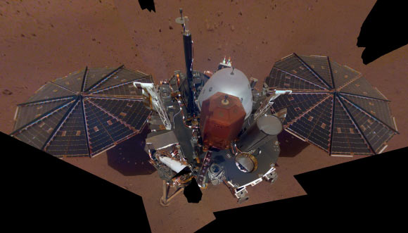 This image shows InSight’s solar panels and deck; on top of the deck are its science instruments, weather sensor booms and UHF antenna. The selfie was taken on December 6, 2018 (Sol 10). The selfie is made up of 11 images which were taken by its Instrument Deployment Camera, located on the elbow of its robotic arm. Image credit: NASA / JPL-Caltech.