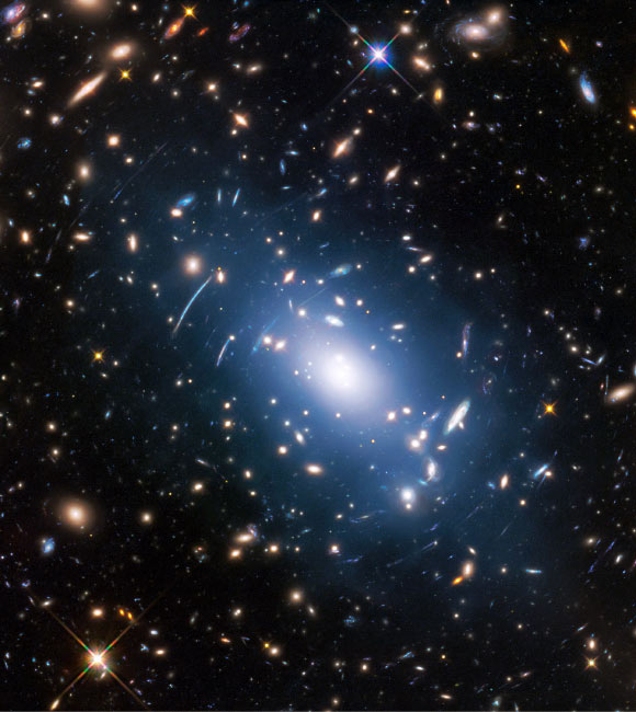The galaxy cluster Abell S1063 was observed by the NASA/ESA Hubble Space Telescope as part of the Frontier Fields Program. The huge mass of the cluster -- containing both baryonic matter and dark matter -- acts as cosmic magnification glass and deforms objects behind it. In the past astronomers used this gravitational lensing effect to calculate the distribution of dark matter in galaxy clusters. A more accurate and faster way, however, is to study the intracluster light (visible in blue), which follows the distribution of dark matter. Image credit: NASA / ESA / M. Montes, University of New South Wales.