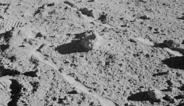 The two Moon-exploring crew men of the Apollo 14 lunar landing mission photographed and collected the large rock pictured just above the exact center of this picture. The rock, casting a shadow off to the left, is the lunar breccia 14321. It lies between the wheel tracks made by the modular equipment transporter (MET) or rickshaw-type portable workbench. A few prints of the lunar overshoes of the crew members are at the left. This photo was made near the boulder field near the rim of Cone Crater. Image credit: NASA.