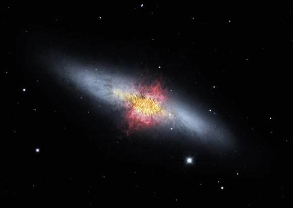 This composite image shows the starburst galaxy Messier 82. The magnetic field detected by SOFIA, shown as streamlines, appears to follow the bipolar outflows (red) generated by the intense nuclear starburst. The image combines visible starlight (gray) and a tracing of hydrogen gas (red) from the Kitt Peak Observatory, with near-infrared and mid-infrared starlight and dust (yellow) from SOFIA and NASA’s Spitzer Space Telescope. Image credit: NASA / SOFIA / E. Lopez-Rodriguez / Spitzer / J. Moustakas et al.