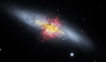 This composite image shows the starburst galaxy Messier 82. The magnetic field detected by SOFIA, shown as streamlines, appears to follow the bipolar outflows (red) generated by the intense nuclear starburst. The image combines visible starlight (gray) and a tracing of hydrogen gas (red) from the Kitt Peak Observatory, with near-infrared and mid-infrared starlight and dust (yellow) from SOFIA and NASA’s Spitzer Space Telescope. Image credit: NASA / SOFIA / E. Lopez-Rodriguez / Spitzer / J. Moustakas et al.