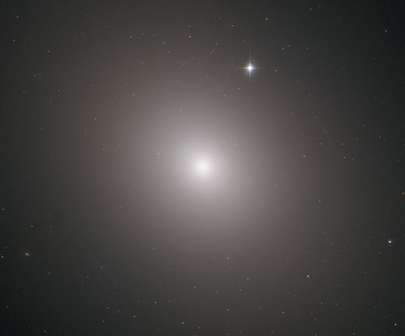 This Hubble image shows the elliptical galaxy Messier 49. The image was made from separate exposures taken in the visible and infrared regions of the spectrum with Hubble’s Advanced Camera for Surveys (ACS) and Wide Field Camera 3 (WFC3). Four filters were used to sample various wavelengths. The color results from assigning different hues to each monochromatic image associated with an individual filter. Image credit: NASA / ESA / Hubble / J. Blakenslee / P Cote et al.