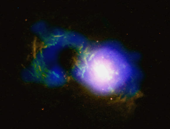 The ‘Teacup’ quasar is causing an ongoing storm. The ‘handle’ is a ring of X-ray (blue) and optical (red and green) light surrounding a giant bubble, shown in the Chandra and Hubble data. This handle-shaped feature, which is located about 30,000 light-years from the galaxy’s central supermassive black hole, was likely formed by one or more eruptions powered by the black hole. Image credit: X-ray -- NASA / CXC / University of Cambridge / G. Lansbury et al; optical - NASA / STScI / W. Keel et al; radio - NRAO / VLA.