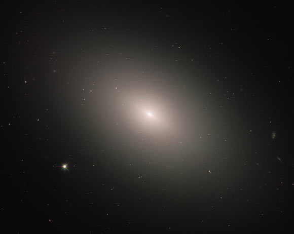 This Hubble image shows the elliptical galaxy Messier 59. This image is a composite of separate exposures acquired by Hubble’s Wide Field and Planetary Camera 2 (WFPC2) and Advanced Camera for Surveys (ACS). Four filters were used to sample various wavelengths. The color results from assigning different colors to each monochromatic image associated with an individual filter. Image credit: NASA / ESA / Hubble / P. Cote.