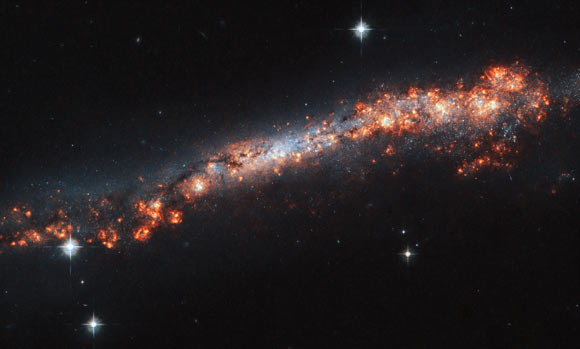 This Hubble image shows the edge-on distorted spiral galaxy NGC 3432. The color image was made from separate exposures taken in the visible region of the spectrum with Hubble’s Advanced Camera for Surveys (ACS). Two filters were used to sample various wavelengths. The color results from assigning different hues to each monochromatic image associated with an individual filter. Image credit: NASA / ESA / Hubble / A. Filippenko / R. Jansen.