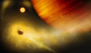 An artist’s impression of an exo-Io undergoing extreme mass loss. The hidden exomoon is enshrouded in an irradiated gas cloud shining in bright orange-yellow, as would be seen with a sodium filter. Patches of sodium clouds are seen to trail the lunar orbit, possibly driven by the gas giant’s magnetosphere. Image credit: Thibaut Roger / University of Bern.