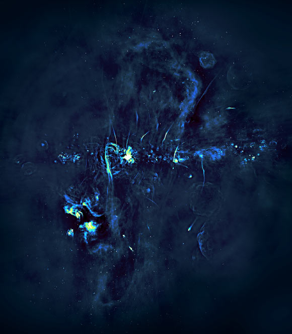 Radio image of the central portions of the Milky Way Galaxy. The Galactic plane is marked by a series of bright features, exploded stars and regions where new stars are being born, and runs horizontally through the image. The black hole at the center of the Milky Way is hidden in the brightest of these extended regions. The radio bubbles discovered by MeerKAT extend vertically above and below the plane of the Galaxy. Many magnetized filaments can be seen running parallel to the bubbles. Image credit: University of Oxford / SARAO.
