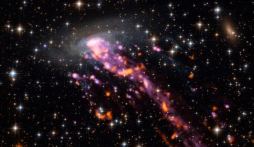 ESO 137-001 is a textbook example of a galaxy that is undergoing stripping by ram pressure: the galaxy and its surroundings were imaged by Hubble; its tail, which traces streams of hydrogen and show up in hues of bright purple, by the MUSE instrument mounted on the VLT; and bright hotspots of carbon dioxide emission from within the system, which show up as flares of orange-red, were spotted by ALMA. Image credit: ALMA / ESO / NAOJ / NRAO / P. Jachym et al.