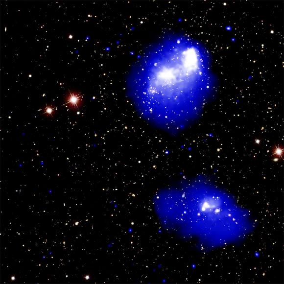 This composite image shows Abell 1758, a quadruple galaxy cluster system about 3 billion light-years away from Earth. In the northern (top) pair seen in the image, the centers of each cluster have already passed by each other once, about 300 to 400 million years ago, and will eventually swing back around. The southern pair at the bottom of the image has two clusters that are close to approaching each other for the first time. X-rays from Chandra are shown as blue and white, depicting fainter and brighter diffuse emission, respectively. This image also includes an optical image from the Sloan Digital Sky Survey (SDSS). Image credit: NASA / CXC / SAO / G. Schellenberger et al / SDSS.