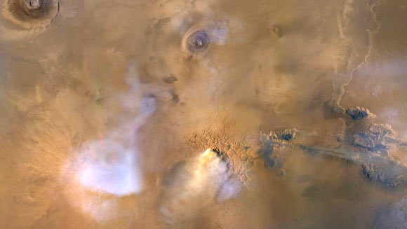 The yellow-white cloud in the bottom-center of this image, taken on November 30, 2010 by NASA’s Mars Reconnaissance Orbiter, is a ‘dust tower’ -- a concentrated cloud of dust that can be lofted dozens of miles above the surface. The blue-white plumes are water vapor clouds. Image credit: NASA / JPL-Caltech / MSSS.