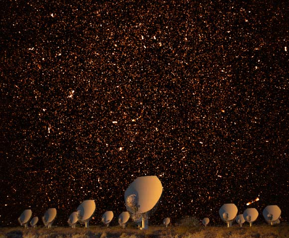 This composite image shows thousands of star-forming galaxies in radio light and the MeerKAT radio telescope array in the South African Karoo semidesert. The brightest spots are luminous radio galaxies powered by supermassive black holes. The myriad faint dots are distant star-forming galaxies like our own Milky Way, too faint to have been detected before now. Because radio waves travel at the speed of light, this image is a time machine that samples the star formation history of the Universe. Image credit: SARAO / NRAO / AUI / NSF.