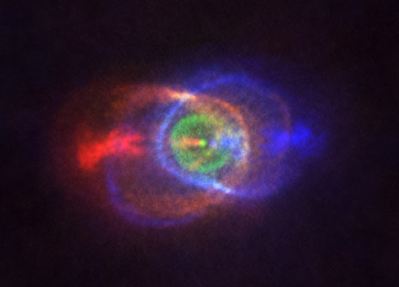 This ALMA image shows the outcome of a stellar fight: a complex and stunning gas environment surrounding the binary system HD 101584. The colors represent speed, going from blue (gas moving the fastest towards us) to red (gas moving the fastest away from us). Jets, almost along the line of sight, propel the material in blue and red. The stars in the binary are located at the single bright dot at the center of the ring-like structure shown in green, which is moving with the same velocity as the system as a whole along the line of sight. Astronomers believe this ring has its origin in the material ejected as the lower mass star in the binary spiraled towards its red-giant partner. Image credit: ALMA / ESO / NAOJ / NRAO / Olofsson et al / Robert Cumming.