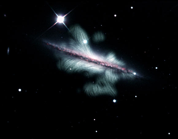 This composite image shows the edge-on spiral galaxy NGC 4217. Magnetic field lines (green), revealed by the VLA, extend far above and below the plane of the galaxy. Image credit: Y. Stein, Centre de Données astronomiques de Strasbourg / NRAO / SDSS / KPNO / J. English, University of Manitoba / R.-J. Dettmar & A. Miskolczi, Ruhr-Universität Bochum / R.J. Rand, U.N.M. / J. Irwin, Queen’s University.