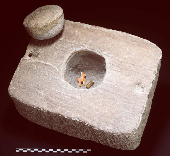 The stone offering box, its cap and contents, comprising a camelid figurine made of shell and a rolled gold foil (scale in cm). Image credit: T. Seguin, Université libre de Bruxelles.
