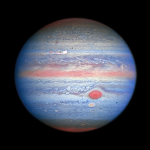 A multiwavelength observation in ultraviolet/visible/near-infrared light of Jupiter obtained by Hubble on August 25, 2020 is giving astronomers an entirely new view of the giant planet. Hubble’s near-infrared imaging, combined with ultraviolet views, provides a unique panchromatic look that offers insights into the altitude and distribution of the planet’s haze and particles. This complements Hubble’s visible-light pictures that show the ever-changing cloud patterns. In this photo, the parts of Jupiter’s atmosphere that are at higher altitude, especially over the poles, look red as a result of atmospheric particles absorbing ultraviolet light. Conversely, the blue-hued areas represent the ultraviolet light being reflected off the planet. A new storm at upper left, which erupted on August 18, 2020, is grabbing the attention of scientists in this multiwavelength view. The ‘clumps’ trailing the white plume appear to be absorbing ultraviolet light, similar to the center of the Great Red Spot, and Red Spot Jr. directly below it. This provides the astronomers with more evidence that this storm may last longer on Jupiter than most storms. Image credit: NASA / ESA / A. Simon, NASA’s Goddard Space Flight Center / M.H. Wong, University of California, Berkeley / OPAL Team.