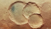 This image shows a triple crater in Noachis Terra, Mars. The largest crater measures 45 km across, and the smallest 28 km. There are also signs of other sizeable craters, such as the round patches of sunken surface seen to the top right and bottom left. This image comprises data gathered by ESA’s Mars Express using its High Resolution Stereo Camera (HRSC) on August 6, 2020. This image was created using data from the nadir and color channels of the HRSC. The nadir channel is aligned perpendicular to the surface of Mars, as if looking straight down at the surface. North is to the right. Image credit: ESA / DLR / FU Berlin / CC BY-SA 3.0 IGO.
