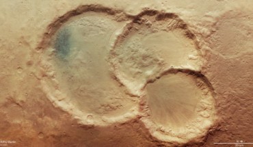 This image shows a triple crater in Noachis Terra, Mars. The largest crater measures 45 km across, and the smallest 28 km. There are also signs of other sizeable craters, such as the round patches of sunken surface seen to the top right and bottom left. This image comprises data gathered by ESA’s Mars Express using its High Resolution Stereo Camera (HRSC) on August 6, 2020. This image was created using data from the nadir and color channels of the HRSC. The nadir channel is aligned perpendicular to the surface of Mars, as if looking straight down at the surface. North is to the right. Image credit: ESA / DLR / FU Berlin / CC BY-SA 3.0 IGO.