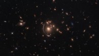 This Hubble image shows the strong-lensing galaxy cluster SDSS J0901+1814. The lensed star-forming galaxy LRG-3-817 is seen as a long arc to the left of the cluster’s central galaxy. The color image was made from separate exposures taken in the visible and infrared regions of the spectrum with Hubble’s Wide Field Camera 3 (WFC3). Five filters were used to sample various wavelengths. The color results from assigning different hues to each monochromatic image associated with an individual filter. Image credit: Hubble / ESA / NASA / S. Allam et al.