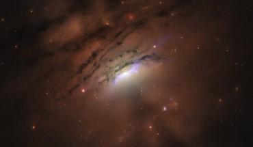 This Hubble image of the nearby active galaxy IC 5063 reveals a mixture of bright rays and dark shadows coming from the blazing core, home of a supermassive black hole. Image credit: Credits: NASA / ESA / Hubble / STScI / W.P. Maksym, CfA.